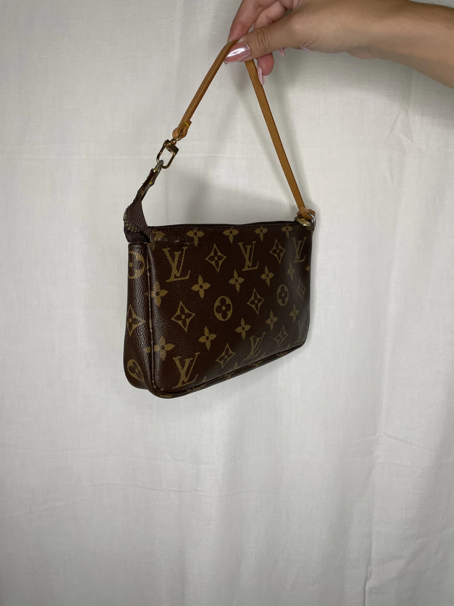 Pochette présentée de trois-quarts, tenue par son anse